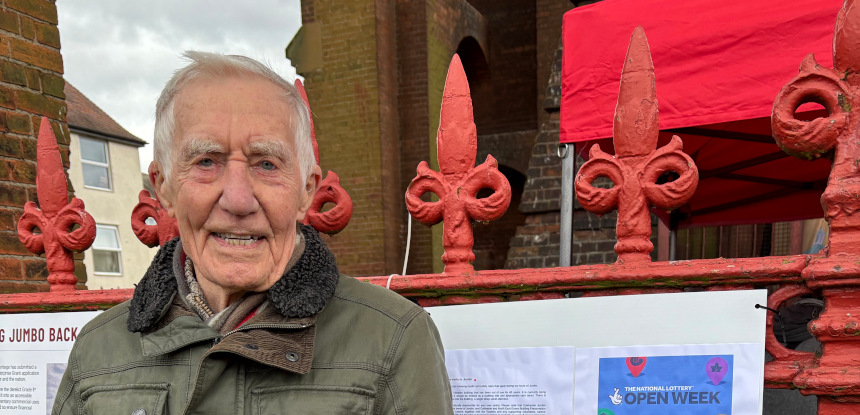 A smiling man in front of red metal railings.